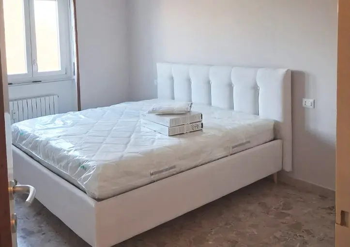 Camera da letto rifatta a Milano con letto imbottito e parete ritinteggiata