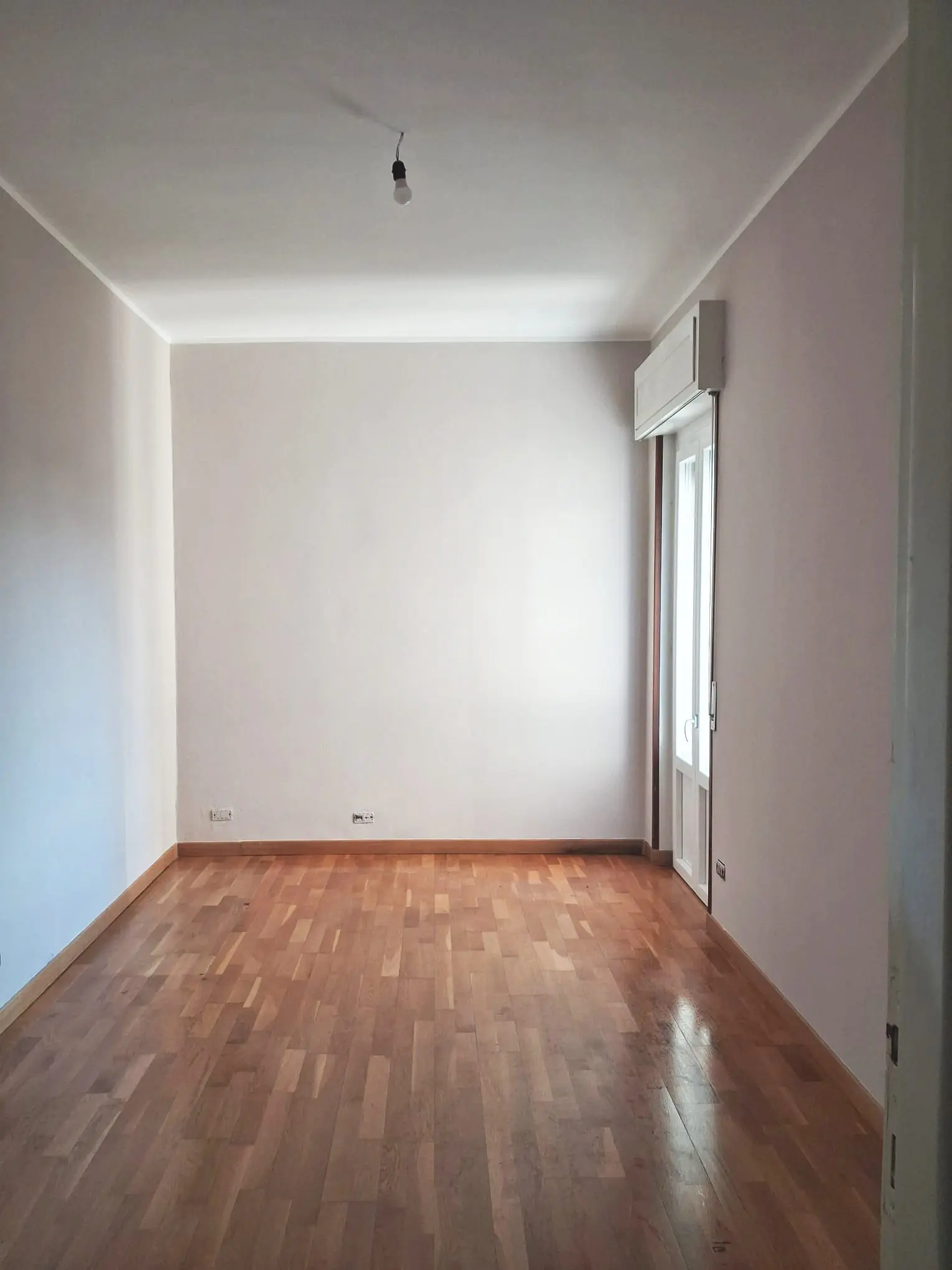 La stanza finita con parquet posato e pareti bianche