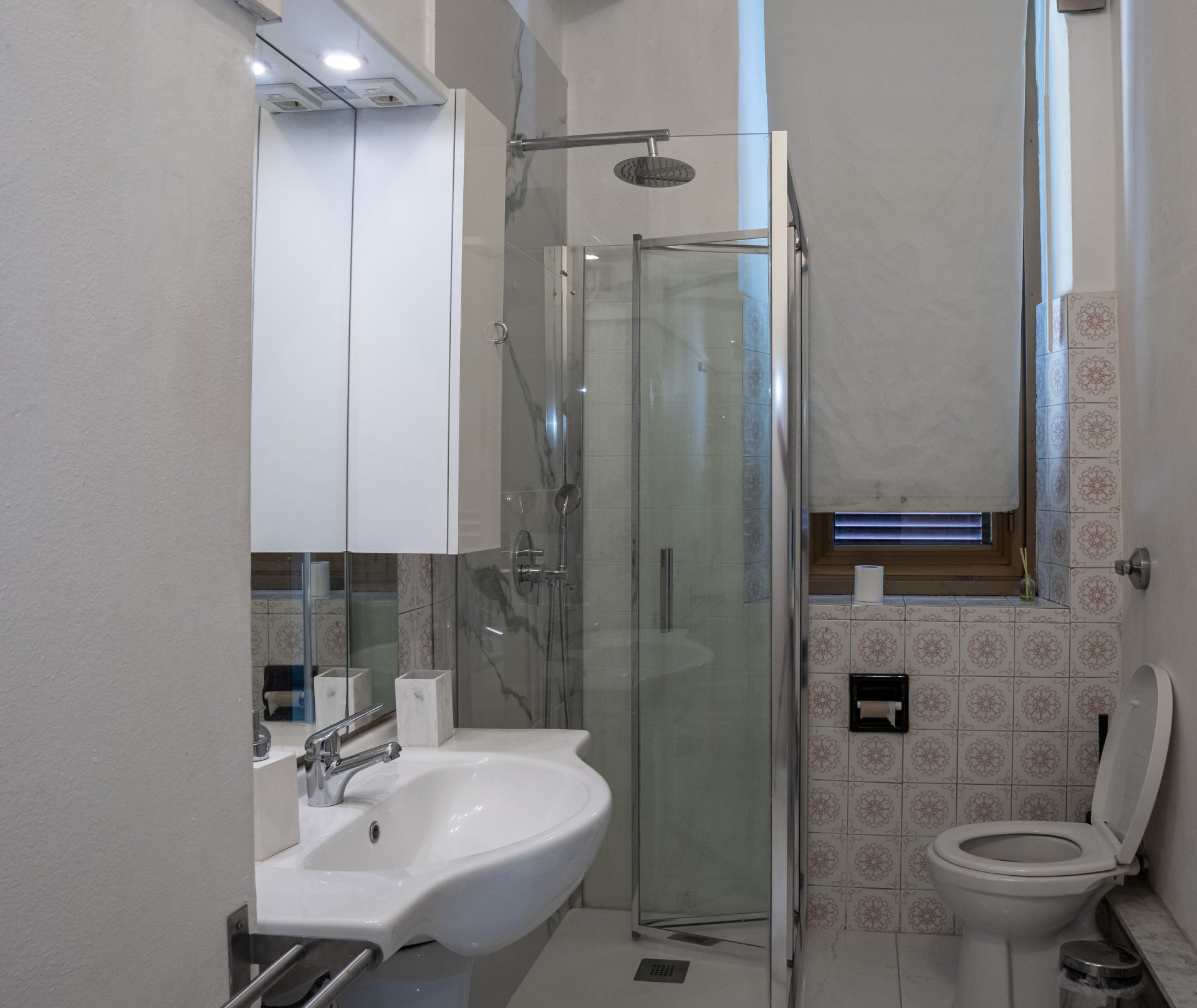 Vista d'insieme del bagno con lavabo, doccia angolare in cristallo e wc