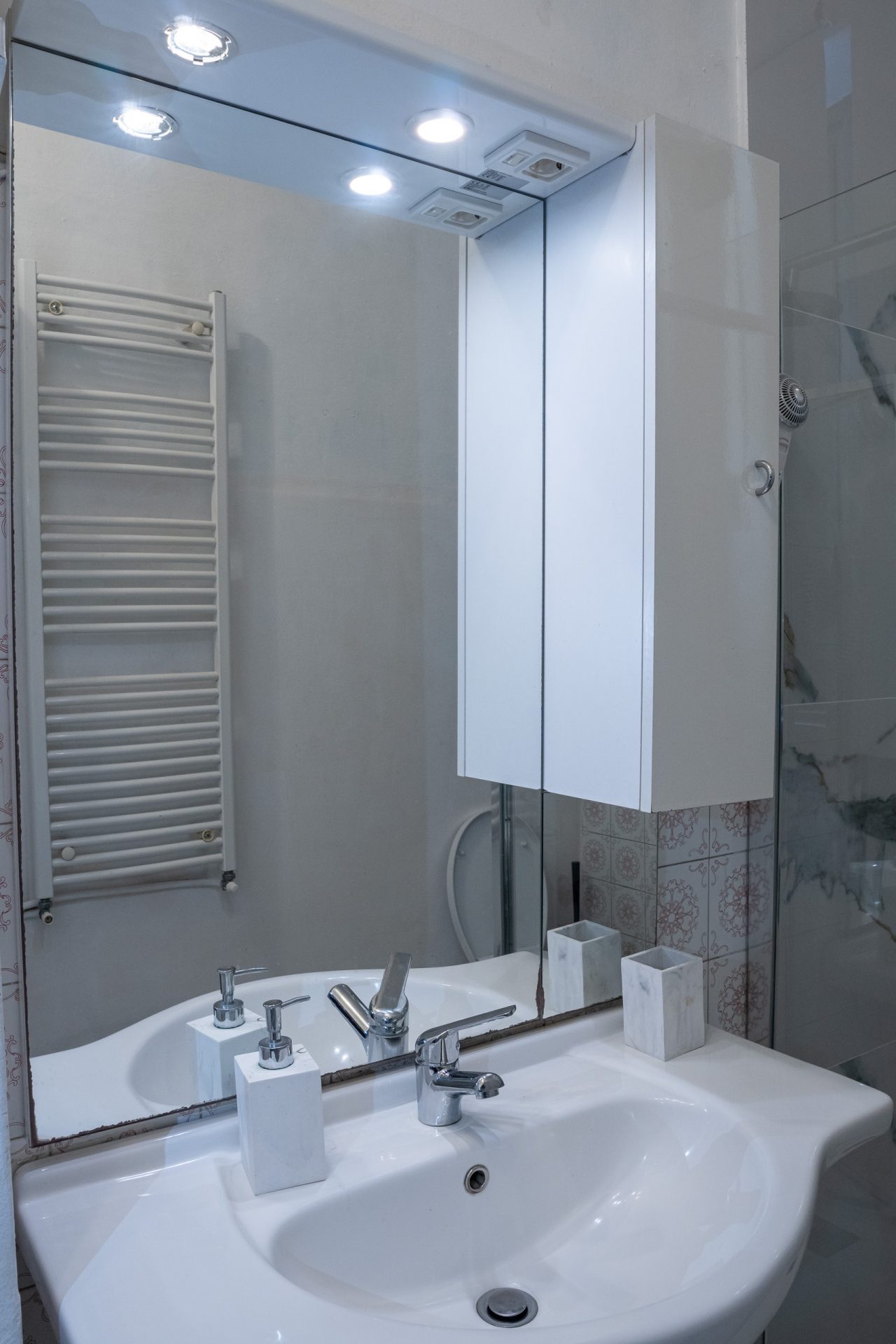 Specchio contenitore con luci integrate sopra il lavabo del bagno di camera