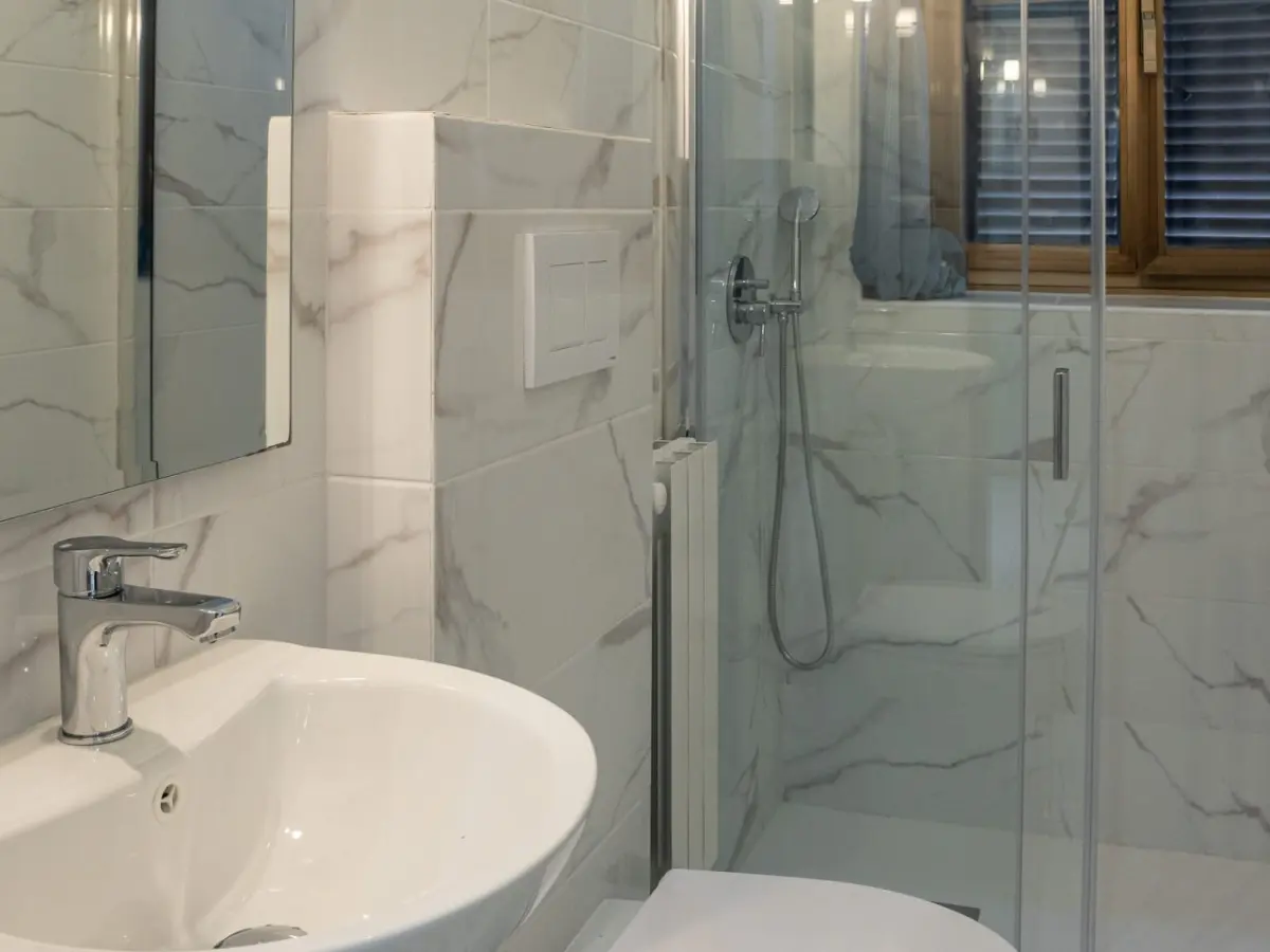 Bagno di camera ristrutturato con lavabo sospeso, wc sospeso e doccia in cristallo