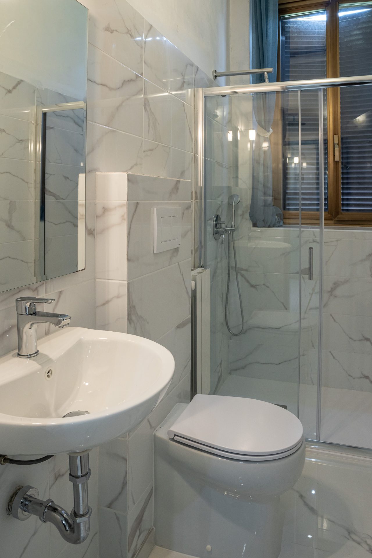 Bagno di camera ristrutturato con lavabo sospeso, wc sospeso e doccia in cristallo