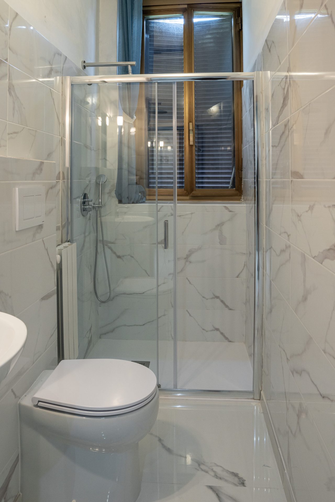 Doccia con porta scorrevole e wc sospeso nel bagno dell'hotel ristrutturato