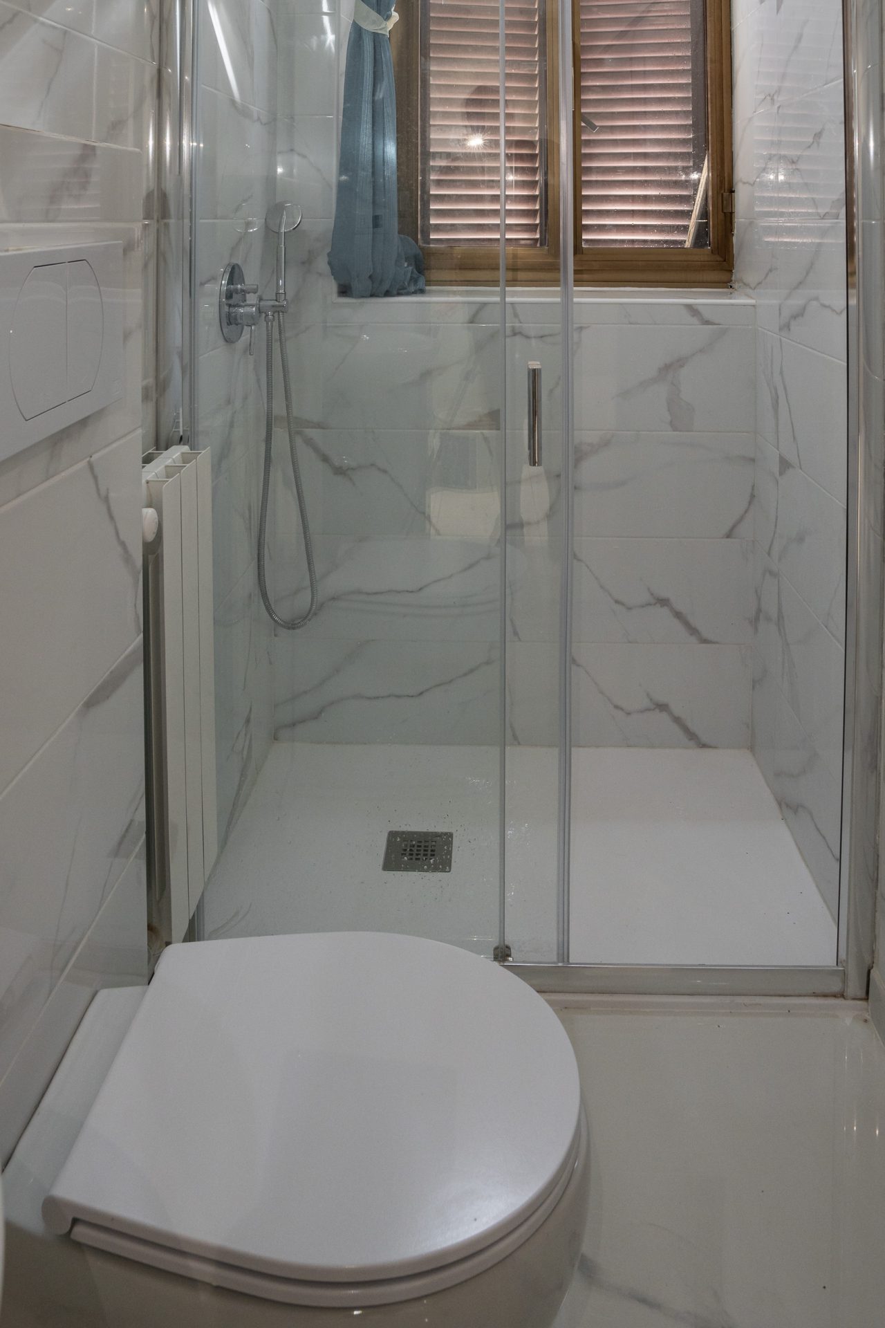 Box doccia con piatto filo pavimento e rivestimento in gres effetto Calacatta