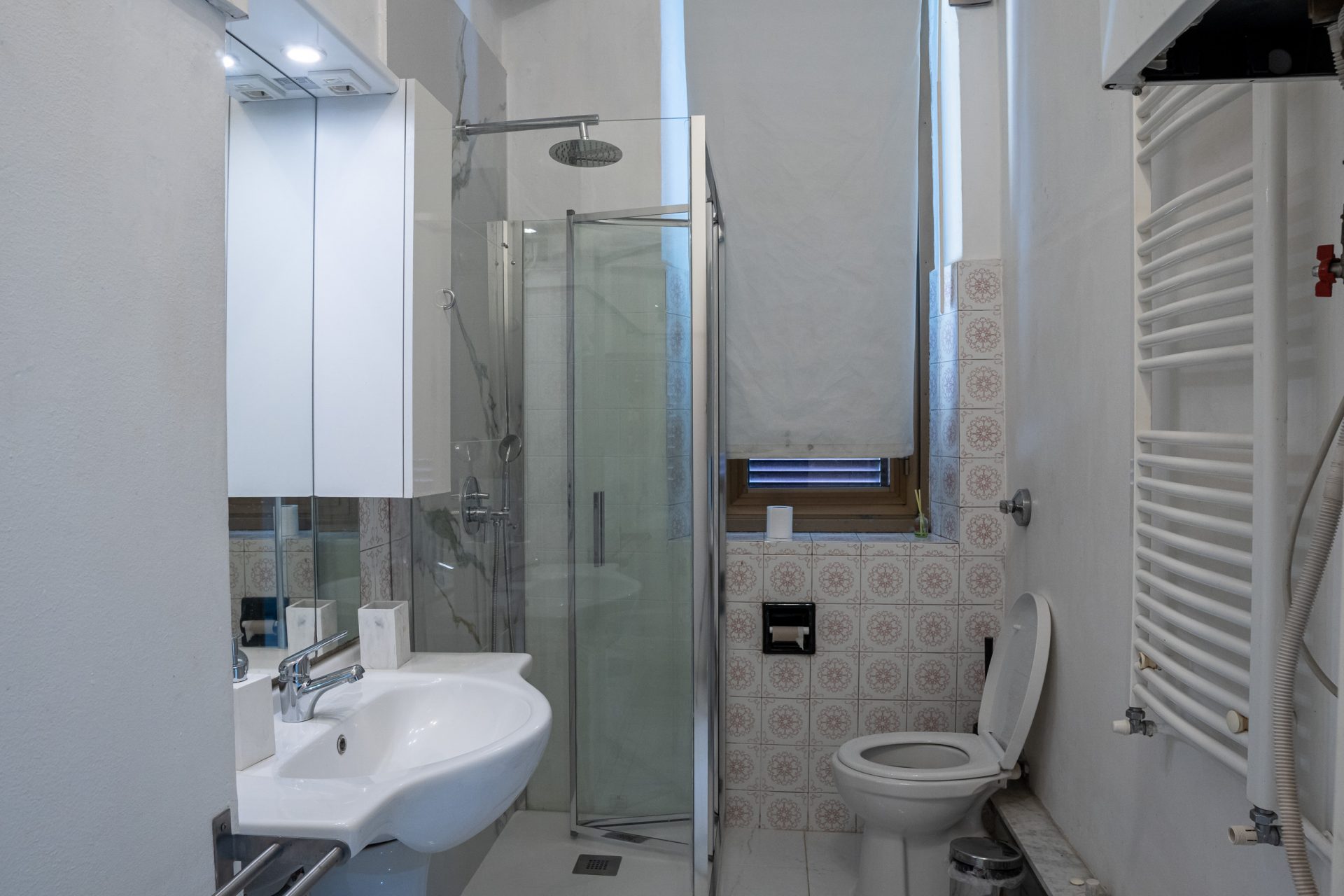 Secondo bagno dell'hotel con box doccia angolare, lavabo e scaldasalviette